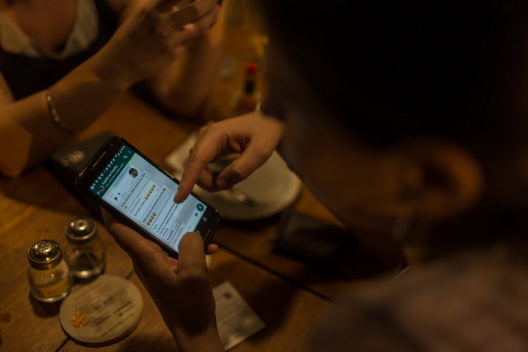 Garota em bar na Vila Madalena tenta, em vão, usar o WhatsApp (Foto: Avener Prado/Folhapress)